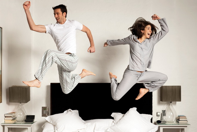 Couple leaping out of bed --- Image by © Simon McComb/cultura/Corbis